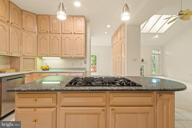 kitchen with a skylight, light brown cabinetry, stainless steel dishwasher, gas stovetop, and light tile patterned floors