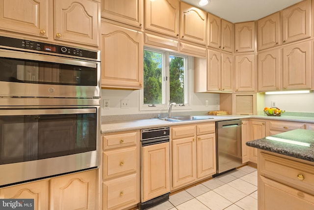 kitchen featuring a sink, appliances with stainless steel finishes, light tile patterned floors, and light brown cabinetry