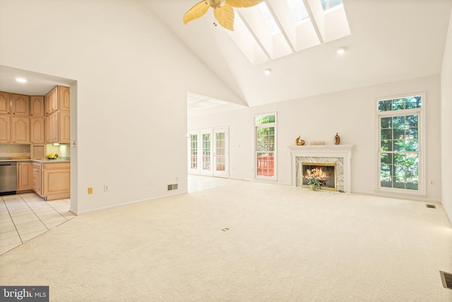 unfurnished living room with a skylight, a high end fireplace, light colored carpet, high vaulted ceiling, and visible vents