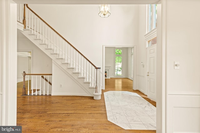 entrance foyer featuring stairs, a chandelier, wood finished floors, and a towering ceiling