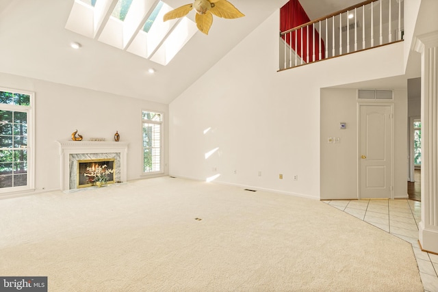 unfurnished living room with a premium fireplace, visible vents, high vaulted ceiling, a skylight, and carpet floors