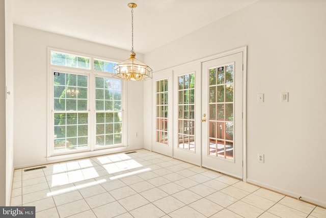 unfurnished dining area featuring french doors, an inviting chandelier, and plenty of natural light