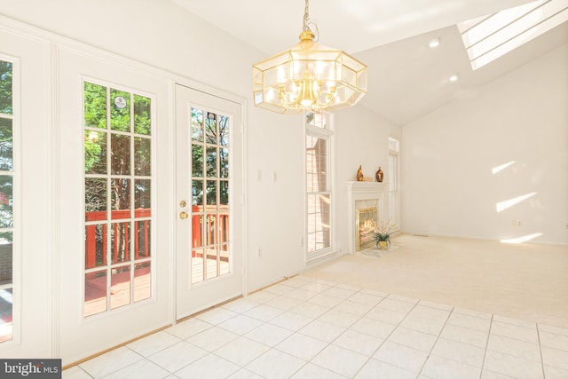 unfurnished dining area featuring a premium fireplace, light tile patterned flooring, a chandelier, light carpet, and vaulted ceiling with skylight