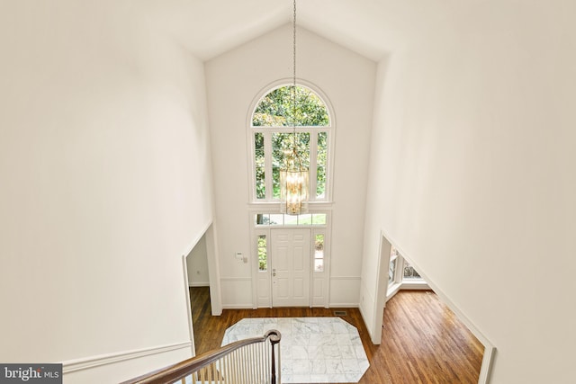 foyer entrance featuring baseboards, high vaulted ceiling, and wood finished floors