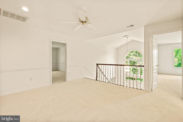 carpeted spare room featuring baseboards, ceiling fan, lofted ceiling, and visible vents