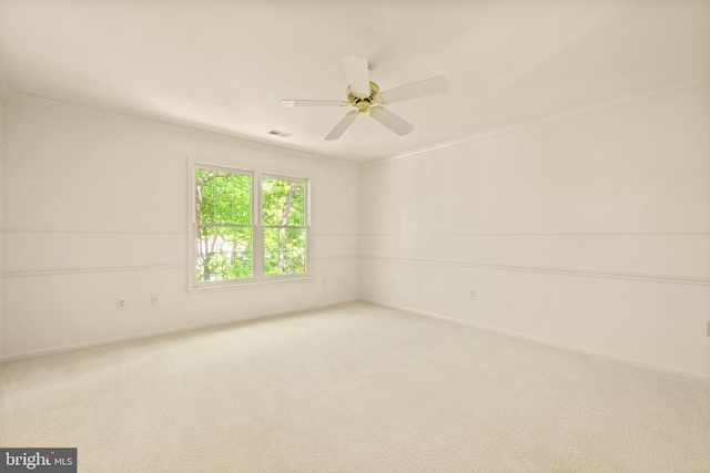spare room featuring carpet flooring, crown molding, baseboards, and a ceiling fan