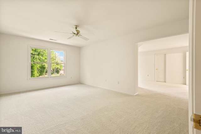 carpeted spare room featuring visible vents, baseboards, and a ceiling fan