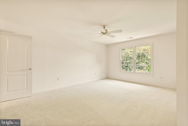 carpeted spare room featuring visible vents, baseboards, and a ceiling fan