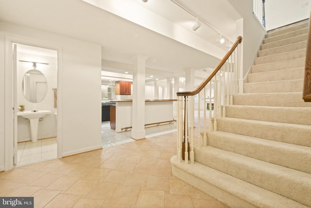 stairs featuring rail lighting and baseboards