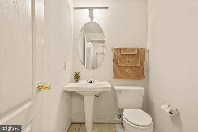 half bathroom with toilet, baseboards, and tile patterned floors