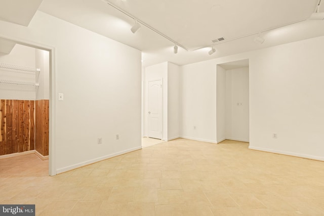 unfurnished room featuring rail lighting, wooden walls, and visible vents