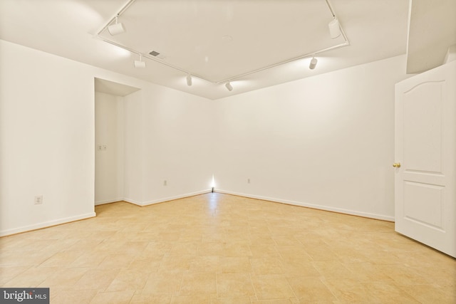 spare room featuring rail lighting, visible vents, and baseboards