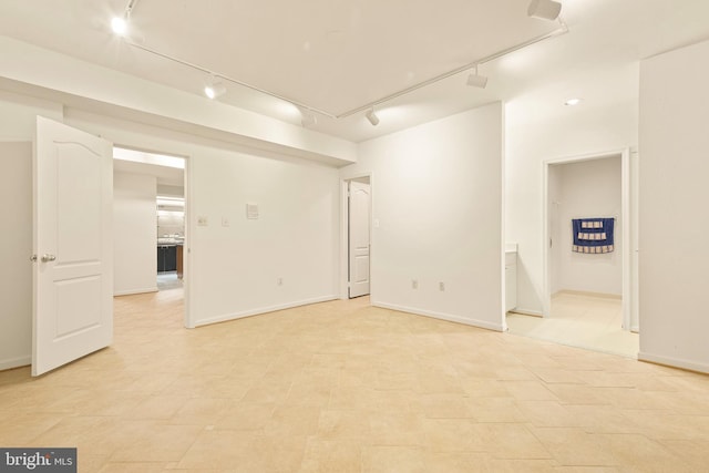 unfurnished room featuring rail lighting