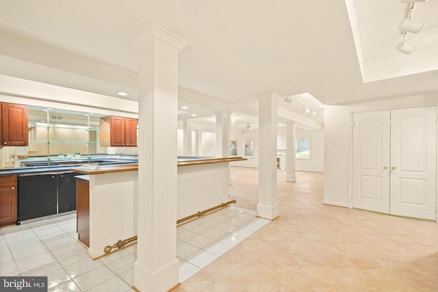 kitchen featuring light tile patterned flooring, dark countertops, brown cabinets, and decorative columns