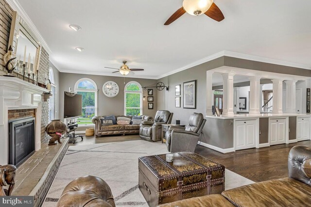 2840 Dunleigh Dr, Dunkirk, MD 20754 - living room featuring a ceiling fan, crown molding, dark wood finished floors, a glass covered fireplace, and ornate columns