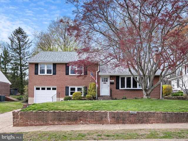 split level home with roof with shingles, a front yard, central AC, brick siding, and a garage