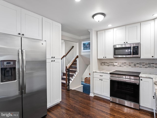 kitchen featuring light stone countertops, dark wood-type flooring, white cabinetry, ornamental molding, and appliances with stainless steel finishes