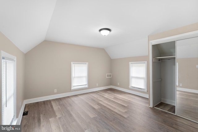 unfurnished bedroom with a closet, multiple windows, and vaulted ceiling