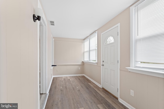 foyer with baseboards, visible vents, and wood finished floors