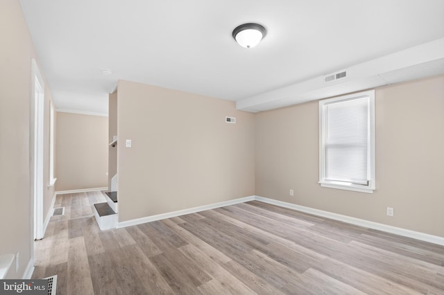empty room featuring baseboards, light wood-type flooring, and visible vents