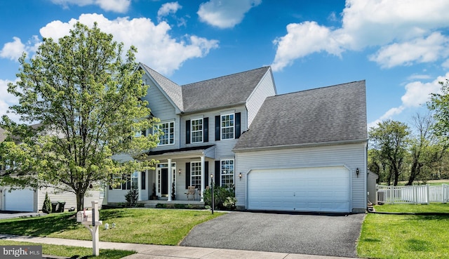 view of front of house featuring covered porch, fence, a front lawn, and aphalt driveway