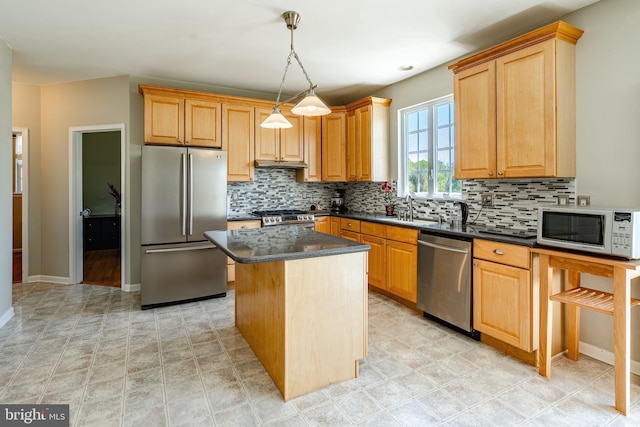 kitchen featuring a kitchen island, appliances with stainless steel finishes, decorative backsplash, and a sink