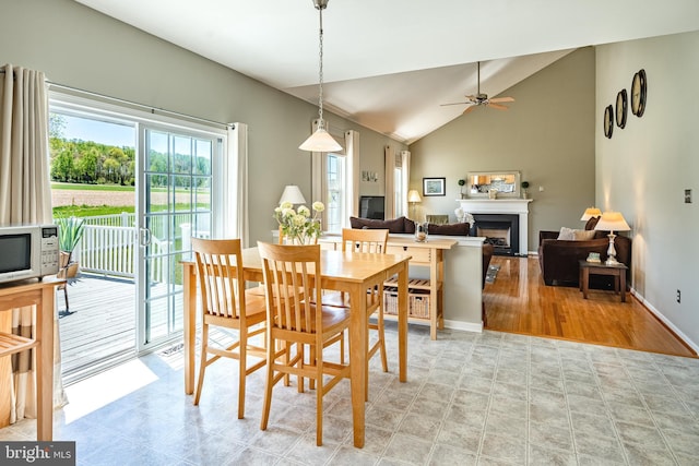 dining space featuring a ceiling fan, baseboards, lofted ceiling, and a fireplace