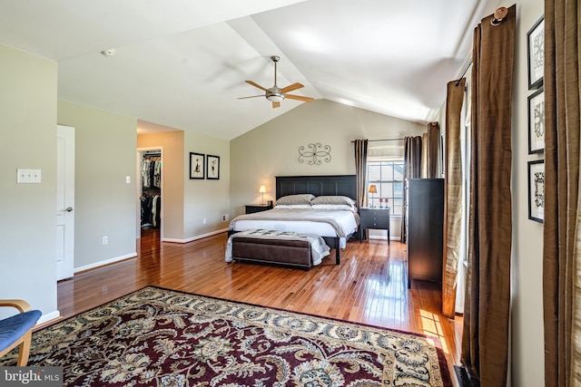 bedroom with lofted ceiling, wood finished floors, baseboards, a spacious closet, and a ceiling fan