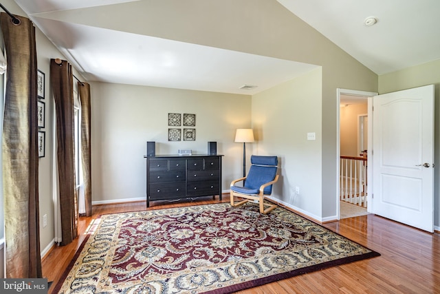 sitting room featuring baseboards, visible vents, wood finished floors, and lofted ceiling