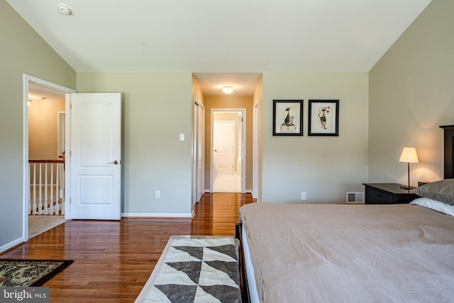bedroom featuring visible vents, baseboards, lofted ceiling, and wood finished floors