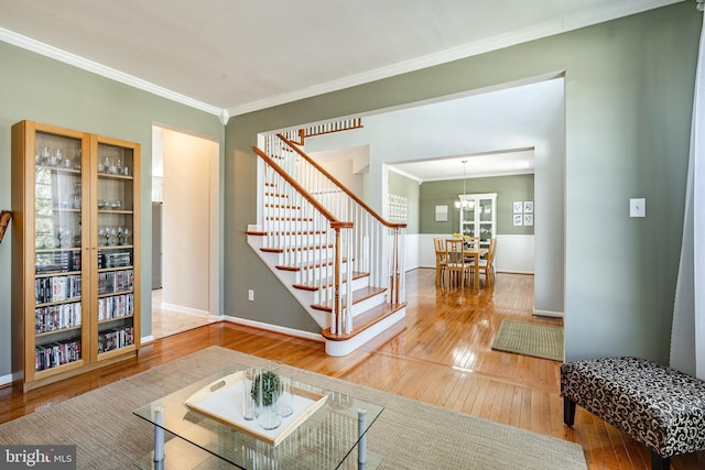 living area with crown molding, baseboards, stairway, hardwood / wood-style flooring, and a notable chandelier