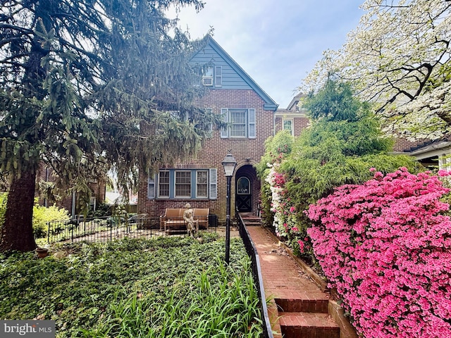 view of front of home featuring brick siding, fence, and an outdoor hangout area