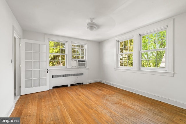 unfurnished room featuring radiator heating unit and light wood-style floors