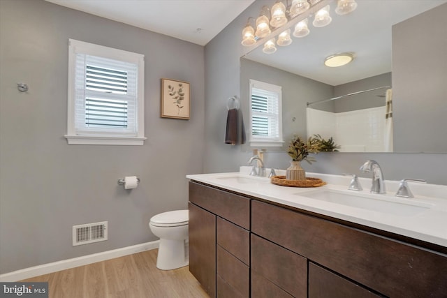 full bath with plenty of natural light, baseboards, wood finished floors, and toilet