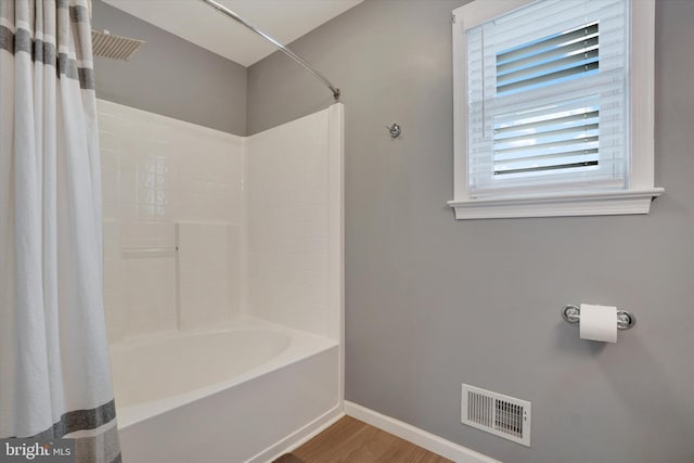 bathroom with wood finished floors, baseboards, and shower / tub combo with curtain