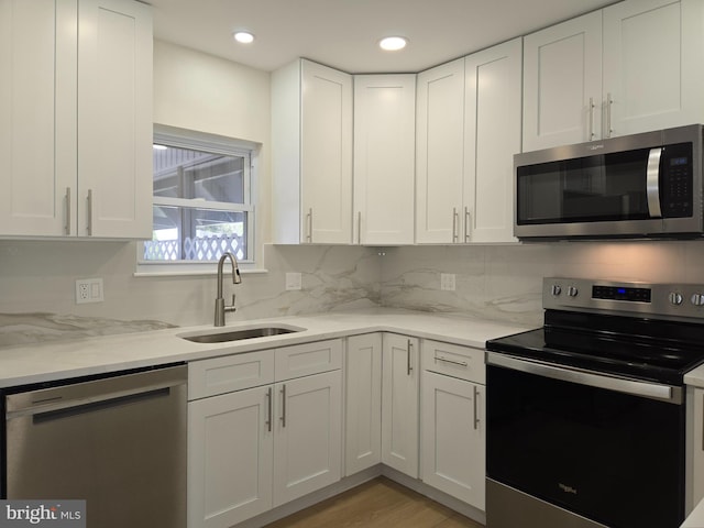 kitchen featuring a sink, light wood-style floors, white cabinetry, appliances with stainless steel finishes, and recessed lighting
