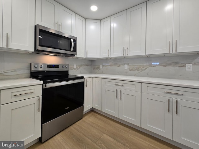 kitchen featuring white cabinetry, tasteful backsplash, stainless steel appliances, and light wood-style floors