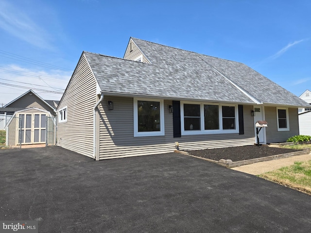 view of front of house featuring a storage unit, an outdoor structure, and roof with shingles