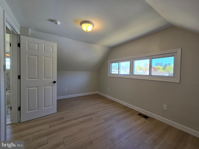 bonus room with lofted ceiling, visible vents, baseboards, and light wood-style flooring