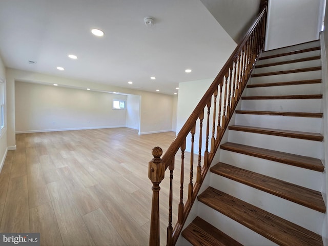 stairway featuring baseboards, wood finished floors, and recessed lighting