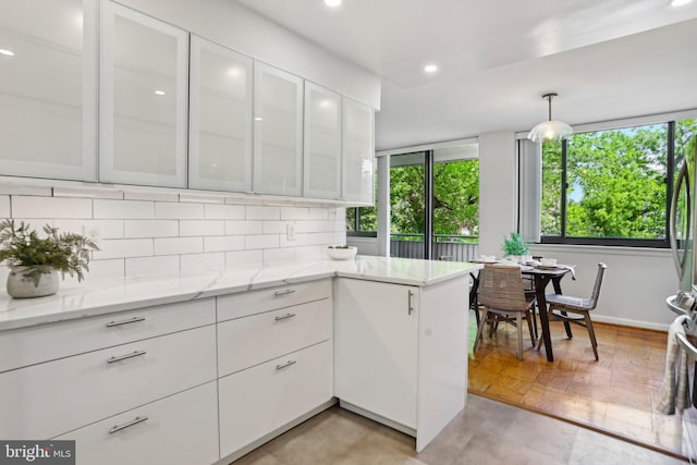 kitchen featuring decorative backsplash, glass insert cabinets, recessed lighting, white cabinetry, and light stone counters