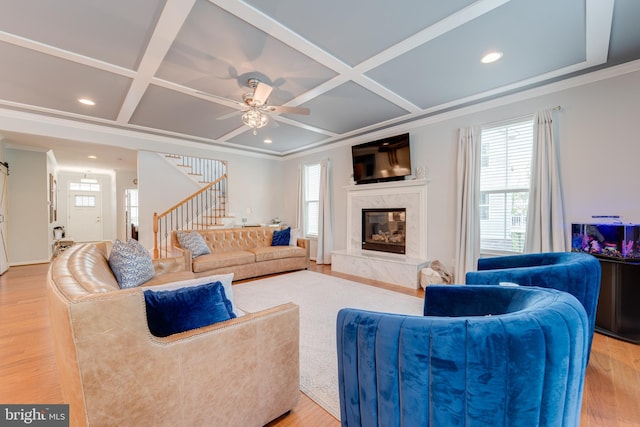 living room featuring stairs, plenty of natural light, a high end fireplace, and coffered ceiling