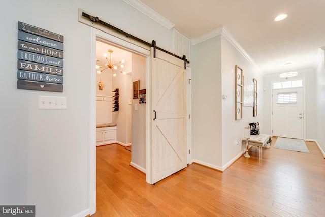 hall featuring a barn door, light wood finished floors, a chandelier, and crown molding