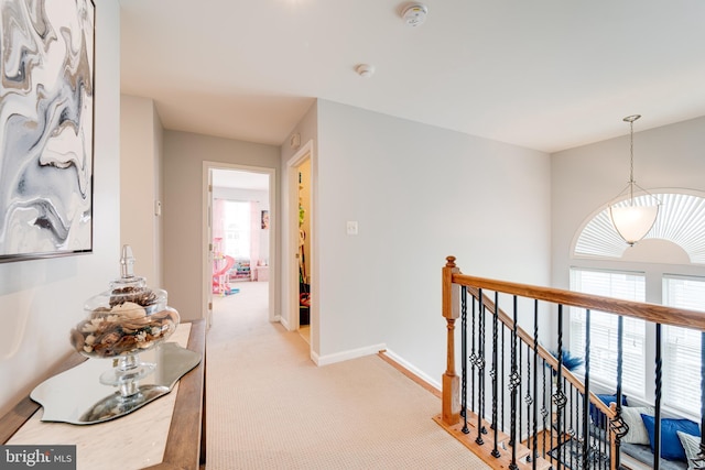 hallway with light colored carpet, an upstairs landing, and baseboards
