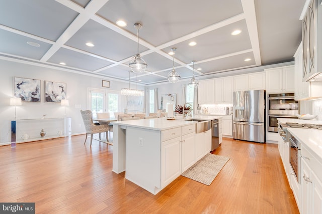 kitchen with white cabinetry, stainless steel appliances, an island with sink, and a sink