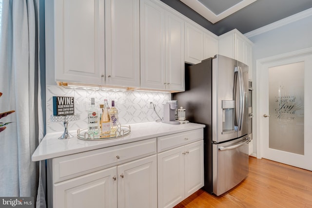 kitchen with stainless steel fridge with ice dispenser, white cabinetry, light wood-type flooring, tasteful backsplash, and ornamental molding