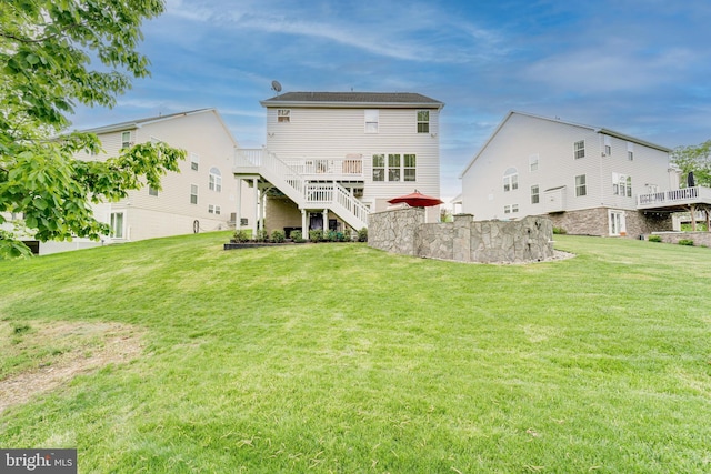 back of house with a deck, stairs, and a lawn