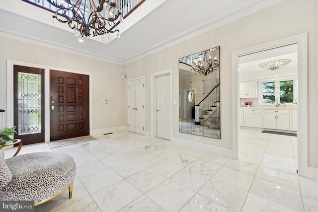 entryway featuring crown molding, baseboards, marble finish floor, an inviting chandelier, and stairs