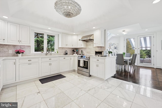 kitchen featuring wall chimney range hood, a notable chandelier, light countertops, electric stove, and recessed lighting