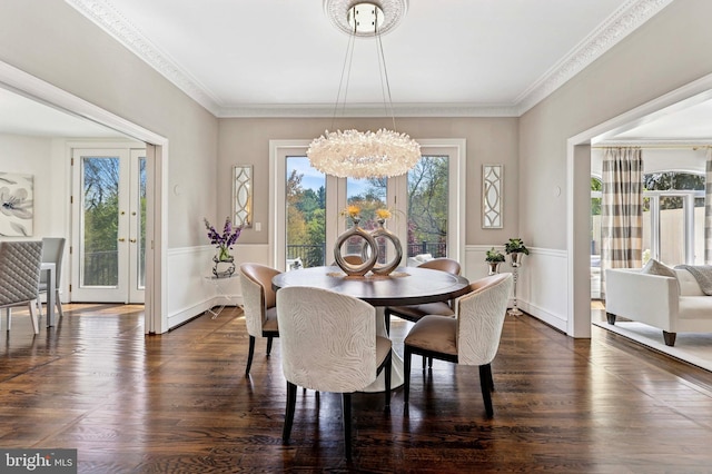 dining room featuring a healthy amount of sunlight, a wainscoted wall, ornamental molding, and a chandelier